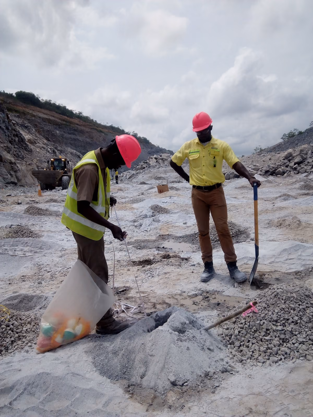 Site crew in high visibility gear charging blast holes at a working quarry