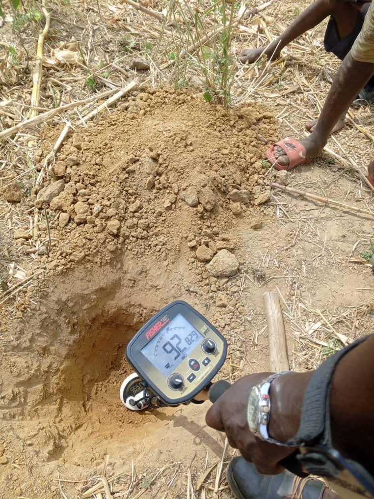 Metal detector reading over a freshly dug test pit during ground survey.
