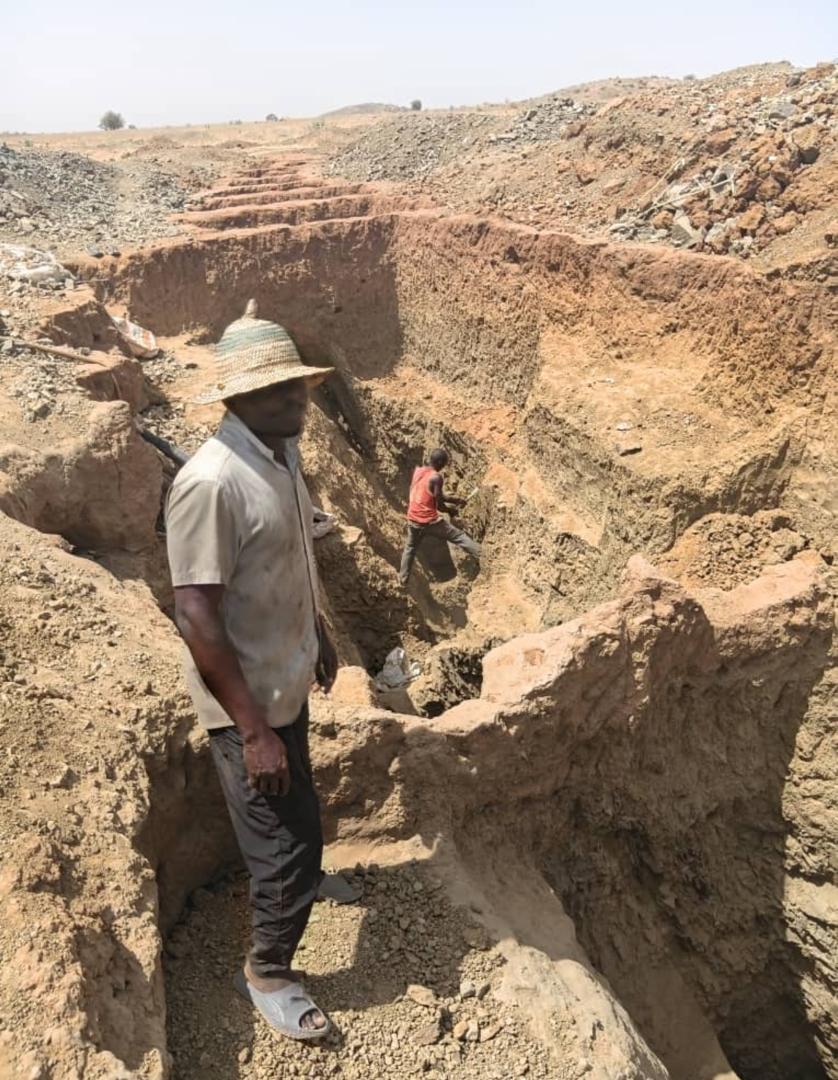 Site visit — team and observers inspecting an open excavation trench.